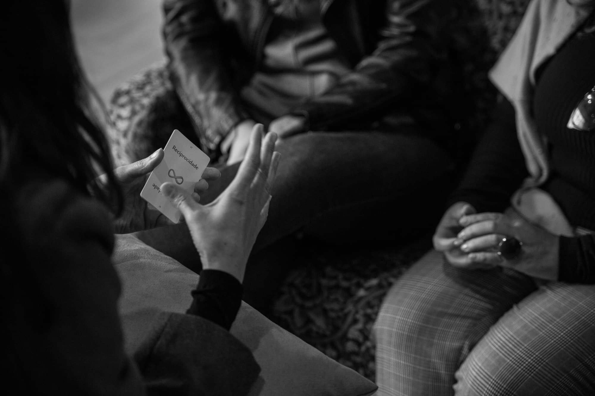 Mãos segurando uma carta do Baralho Konekti durante uma roda de prática